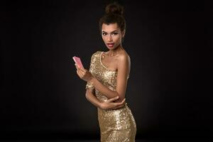 Woman winning - Young woman in a classy gold dress holding two cards, a poker of aces card combination. Emotions photo