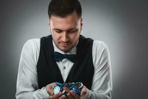 Young man in shirt and waistcoat shows his poker chips, studio shot photo