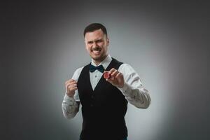 Young man in shirt and waistcoat shows his poker chips, studio shot photo