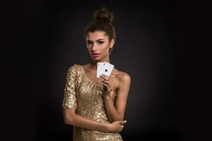 Woman winning - Young woman in a classy gold dress holding two aces, a poker of aces card combination. photo