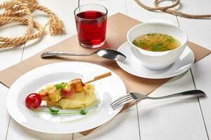 Set lunch of chicken broth, mashed potatoes with chicken skewer, berry juice photo