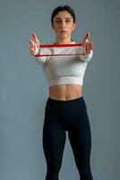 Girl performing arm and shoulder exercises with resistance band on grey background photo