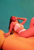 Woman in swimsuit lying with closed eyes on yellow inflatable mattress photo