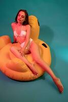 Woman in white swimsuit sitting on yellow air mattress photo