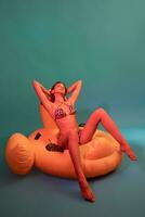 Relaxed woman in swimsuit sitting on yellow inflatable pool float photo