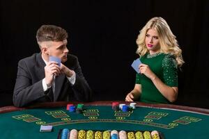 View of young, confident, man with the lady while he's playing poker game. Man bets in poker photo