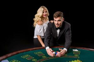 View of young, confident, man with the lady while he's playing poker game. photo