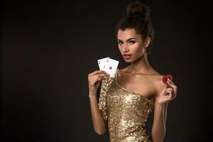 mujer victorioso - joven mujer en un de buen tono oro vestir participación dos ases y dos rojo papas fritas, un póker de ases tarjeta combinación. foto