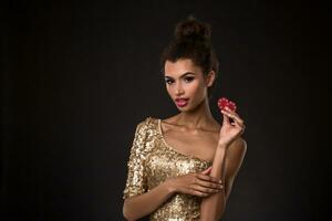 Woman winning - Young woman in a classy gold dress holding two red chips, a poker of aces card combination. photo