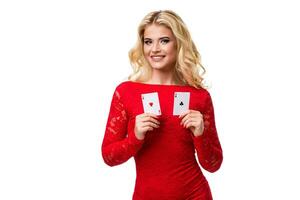 Caucasian young woman with long light blonde hair in evening outfit holding playing cards. Isolated. Poker photo