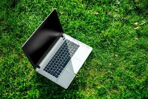 Laptop with blank screen on green lawn photo