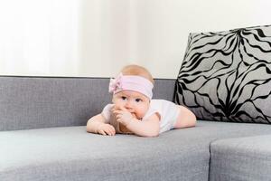 retrato de un bebé niña con un vendaje y un arco en su cabeza en un sofá foto
