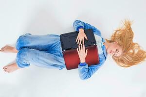 young woman lying on the floor in his pajamas with a laptop. photo