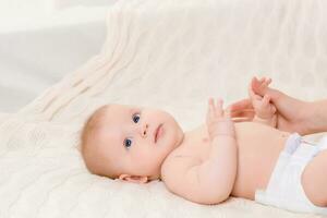 Happy baby lying on a white plaid in the bedroom photo