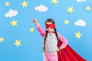 pequeño niño obras de teatro superhéroe niño en el antecedentes de brillante azul pared. foto