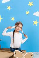 Little child girl in a pilot's costume is playing and dreaming of flying over the clouds. photo