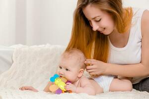 Mother and child on a white bed. Mom and baby girl in diaper playing in sunny bedroom. photo