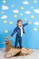 Little child girl in a pilot's costume is playing and dreaming of flying over the clouds. photo