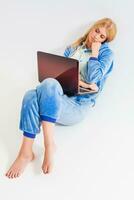 girl in pajamas with a laptop lying on the floor photo