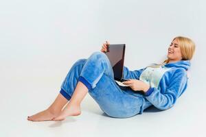 girl in pajamas with a laptop lying on the floor photo