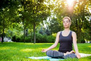 Young woman doing yoga exercises in the summer city park. photo