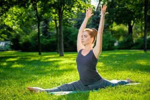 Young woman doing yoga exercises in the summer city park. photo