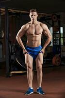 Man standing strong in the gym and flexing muscles photo