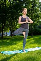 Young woman doing yoga exercises in the summer city park. photo