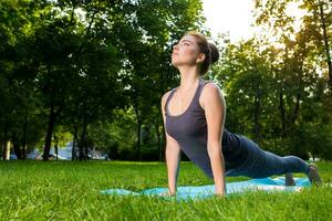 Young woman doing yoga exercises in the summer city park. photo