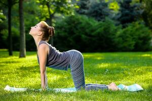 Young woman doing yoga exercises in the summer city park. photo