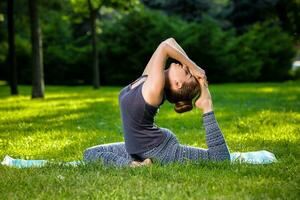 Young woman doing yoga exercises in the summer city park. photo