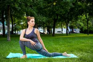 joven mujer haciendo yoga ejercicios en el verano ciudad parque. foto