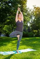 Young woman doing yoga exercises in the summer city park. photo