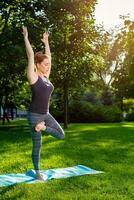 Young woman doing yoga exercises in the summer city park. photo