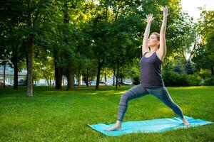 Young woman doing yoga exercises in the summer city park. photo