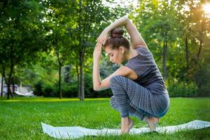 Young woman doing yoga exercises in the summer city park. photo