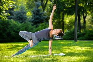 Young woman doing yoga exercises in the summer city park. photo