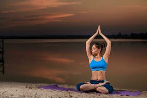 yoga a puesta de sol en el playa. foto