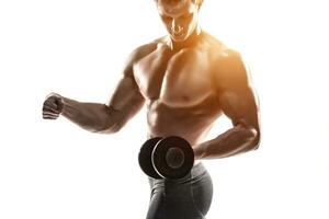 Athletic man showing muscular body and doing exercises with dumbbells photo