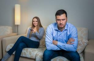 Portrait of couple sitting on sofa watching television. photo