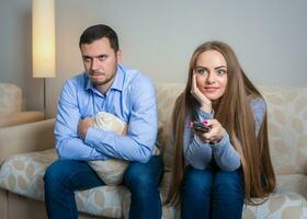 Portrait of couple sitting on sofa watching television. photo