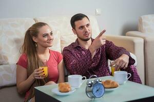 Cute young couple having breakfast, eating croissants, drinking orange juice. photo