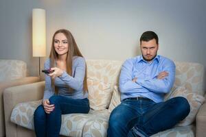 Portrait of couple sitting on sofa watching television. photo