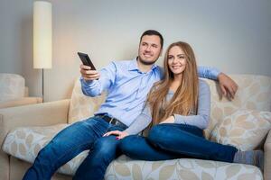 Happy couple sitting on sofa watching television together photo