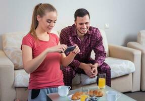 Cute young couple having breakfast, photographs at mobile phone photo