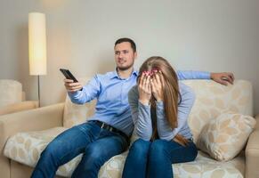 Portrait of couple sitting on sofa watching television. photo