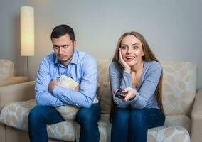 Portrait of couple sitting on sofa watching television. photo