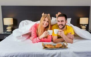 contento joven Pareja teniendo desayuno bandeja en cama a hogar foto