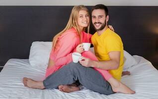 Happy young couple having breakfast tray on bed at home photo