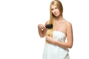 joven mujer en un toalla cepillado su cabello. foto